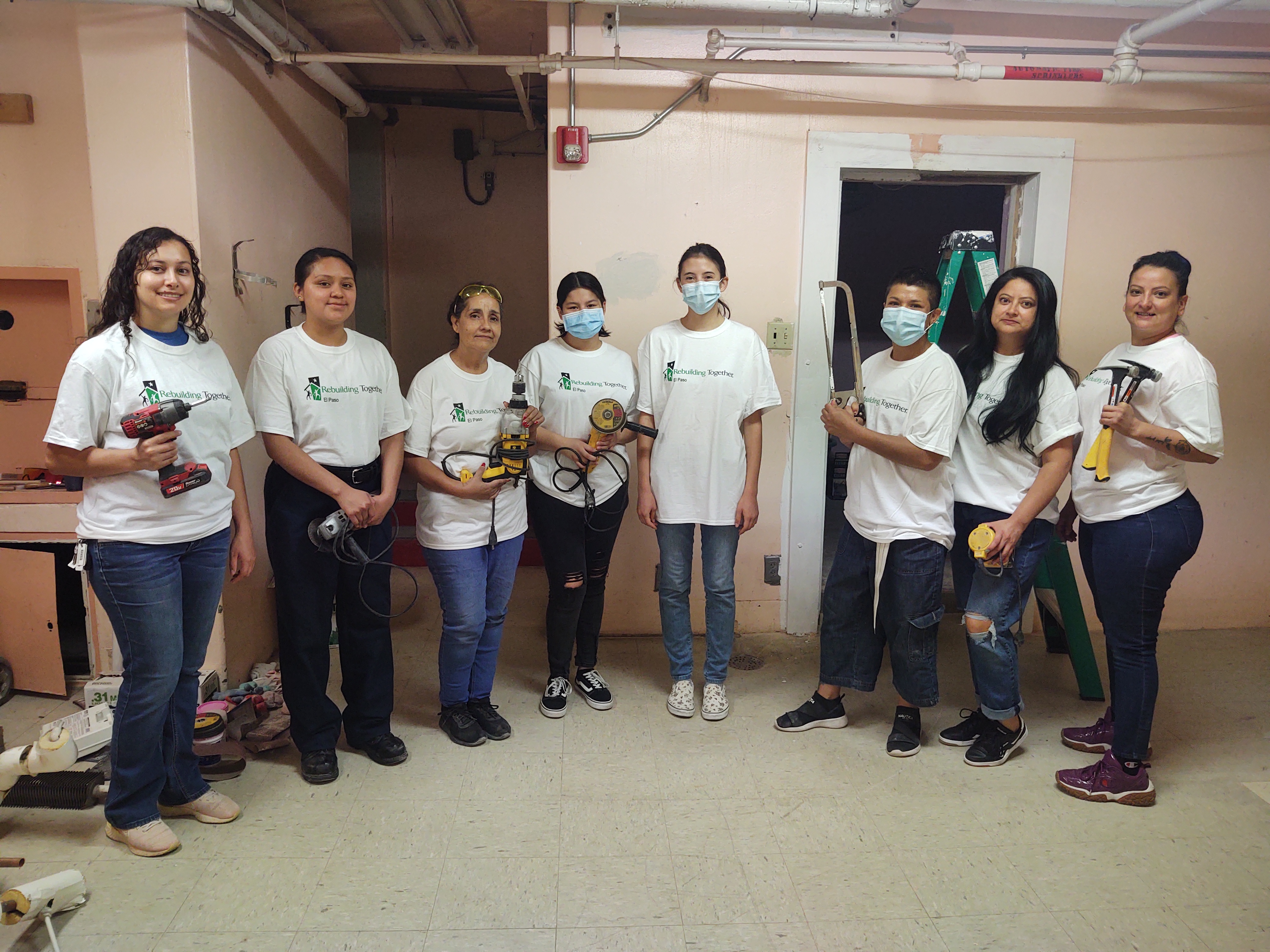 A group of female Rebuilding Together El Paso volunteers holding tools and smiling. 